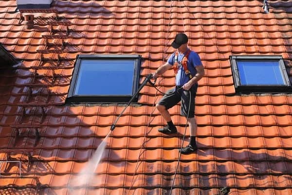 Professionnel en train de réaliser un nettoyage de toiture en Couvreur Toulouse avec nettoyeur haute pression